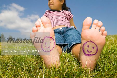 Young girl with smiley faces on bare feet