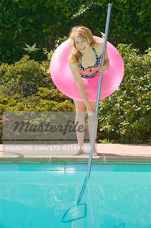Young woman poolside with pink floatation device