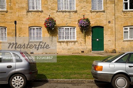 Cars parked outside stone cottages, Cotswolds, United Kingdom