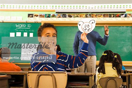 Boy holding drawing over teacher’s face