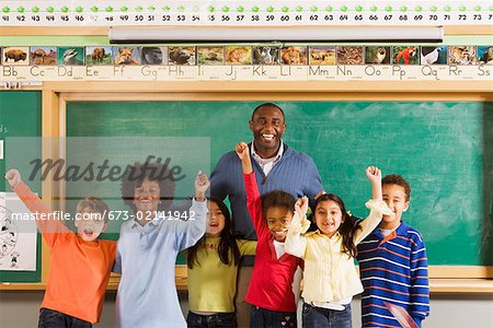 Male teacher and students cheering in classroom