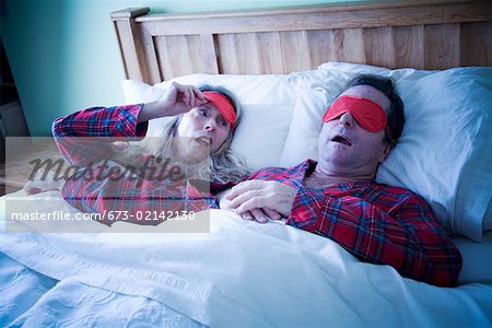 Woman peeking at man wearing eye mask