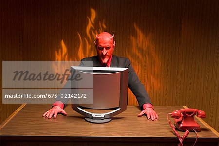 Businessman dressed as devil looking at computer