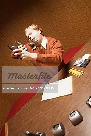 Businessman at desk using multiple telephones