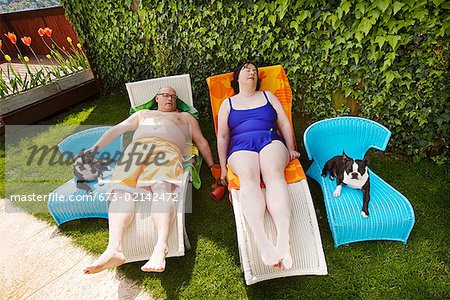 Couple relaxing on lawn chairs in backyard