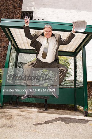 Businessman jumping at bus stop