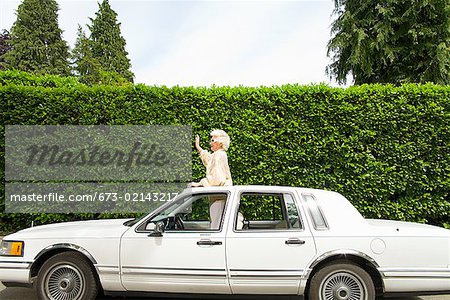 Senior woman standing in sunroof of car