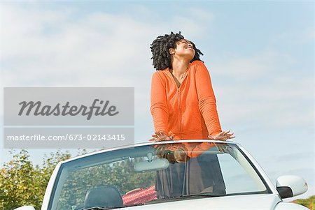 African woman standing in convertible car