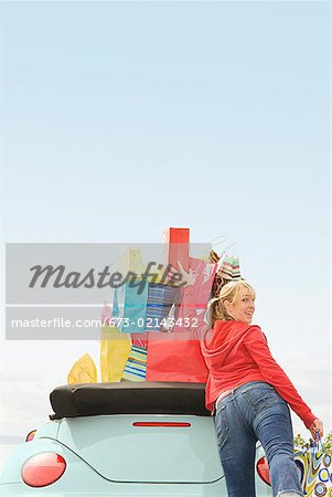 Woman reaching for shopping bag stack in car