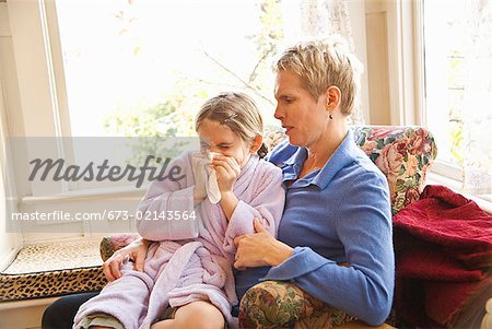 Mother watching sick daughter blow nose