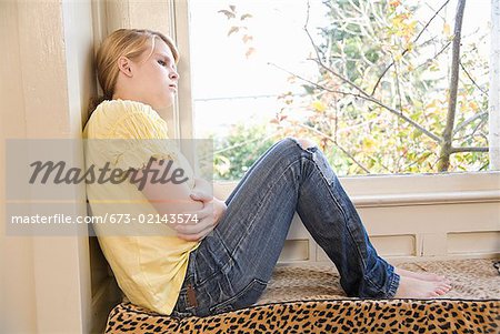 Teenaged girl sitting next to window