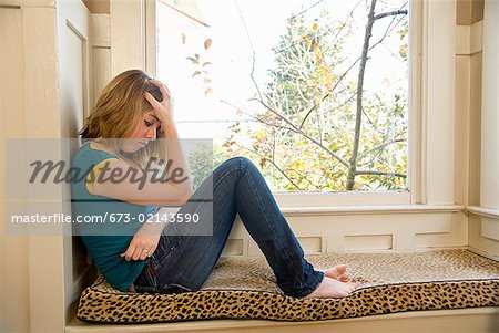 Teenaged girl sitting next to window