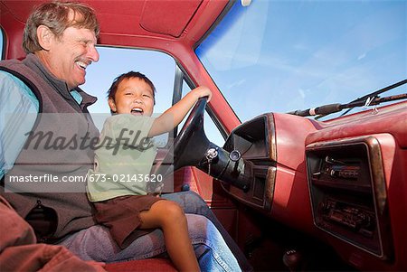 Grandfather with grandson on lap in car