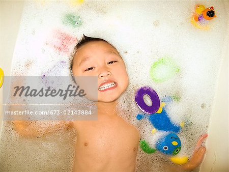 Asian boy floating in bathtub