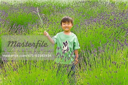 Asian boy holding plant in meadow