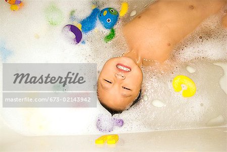 Asian boy floating in bathtub