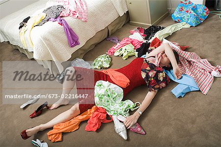 Woman on bedroom floor buried under clothing