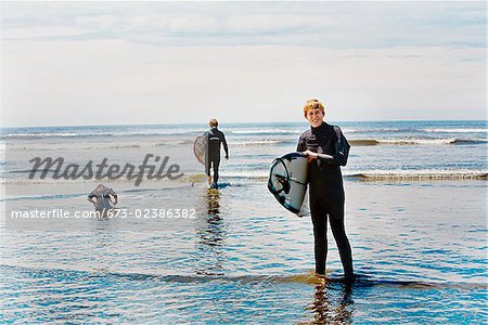 Surfers holding surfboards on the beach, Washington State, USA
