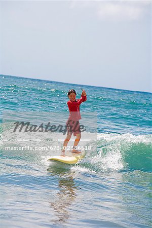 Girl surfing in the sea and holding a mobile phone