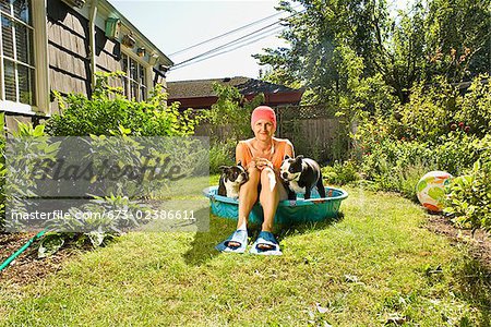 Woman sitting between two Boston Terriers in a wading pool