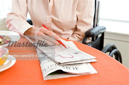Woman in a wheelchair at breakfast searching classifieds