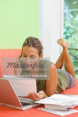 woman paying bills on couch