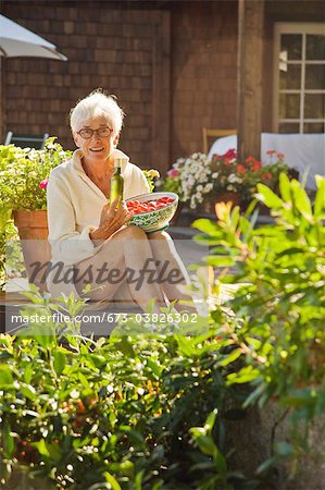 senior woman holding tomatoes outdoors