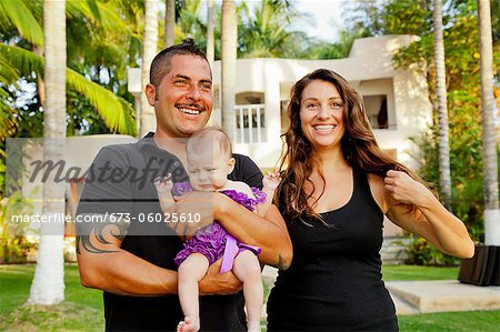 Portrait of young family in front of large house