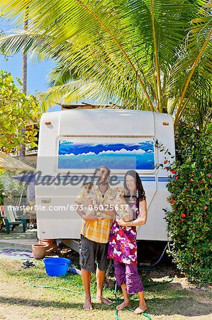 Man and woman holding small dogs at rear of camper