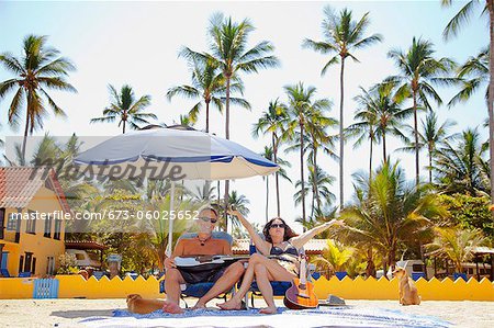 Happy man and woman in beach chairs with guitars and dogs