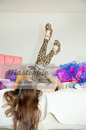 Woman on bed surrounded by shopping bags