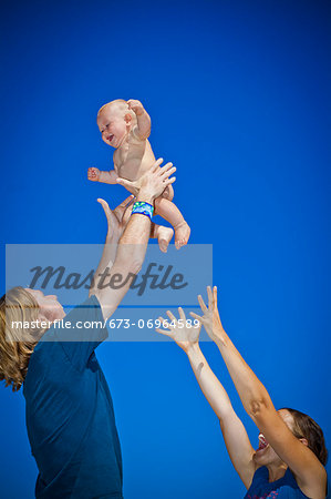Parents holding baby up in air