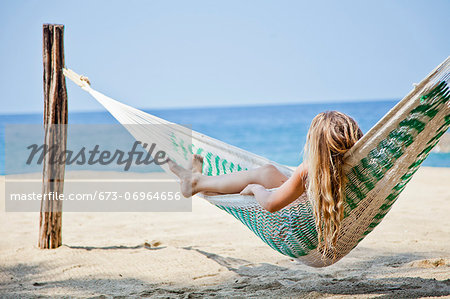 Young woman in hammock on beach