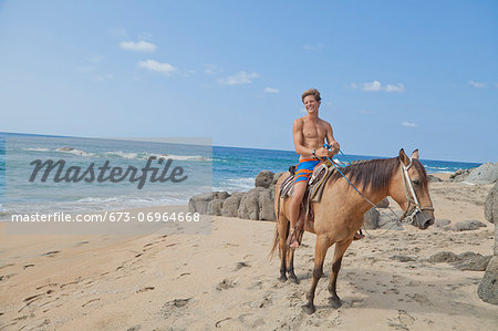 Young man riding horse on beach