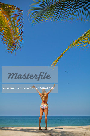 Woman in bikini jumping on beach