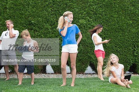 Family of five all using technology outdoors