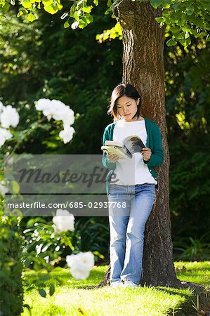 Young woman reading under a tree