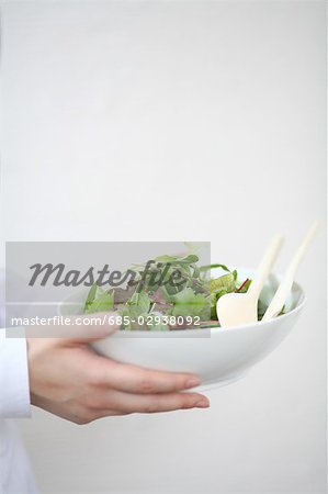 A young woman carrying a bowl of salad