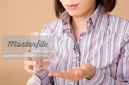 A woman holding glass of water and pills
