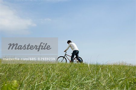 Young man pushing bicycle