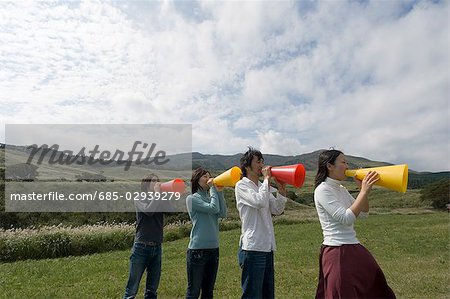 Four young people shouting into megaphones