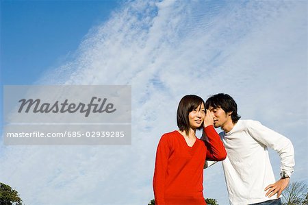 Young man whispering to young woman