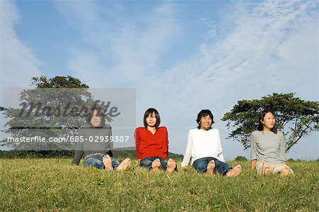Four young people sitting in field