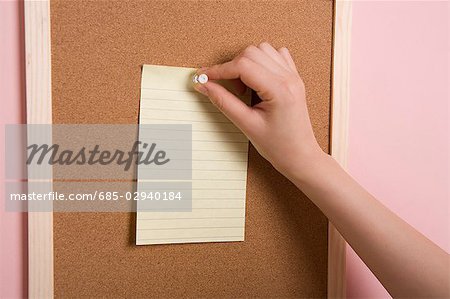 Woman's hand pinning memo to bulletin board