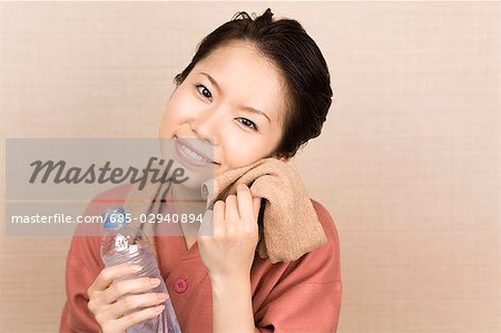 Young woman wiping face with towel