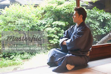 Young man in kimono sitting at veranda