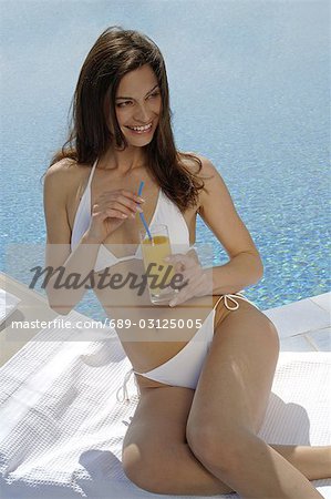 Woman in bikini with a drink at the swimming pool
