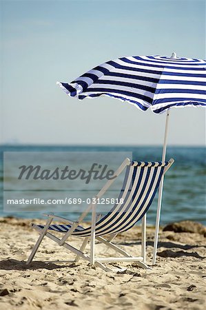 Blue and white sunshade and deckchair on the beach