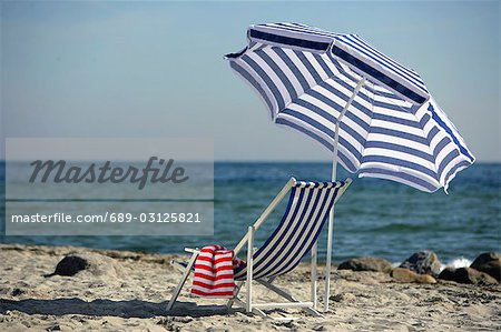 Blue and white sunshade and deckchair on the beach