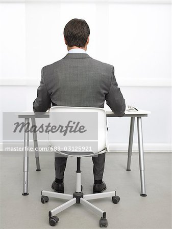 Rearview Of A Business Man Sitting At His Desk Stock Photo